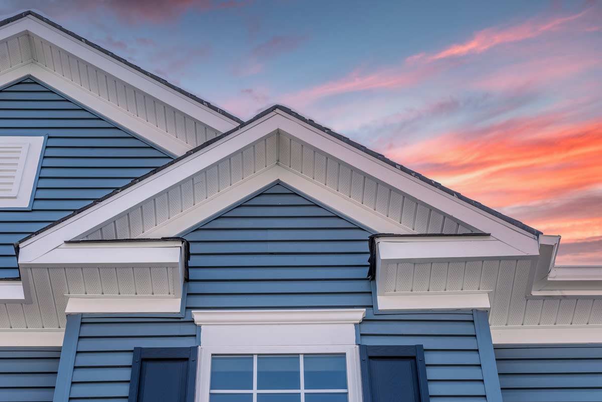 top part of blue house with white trim and sunset