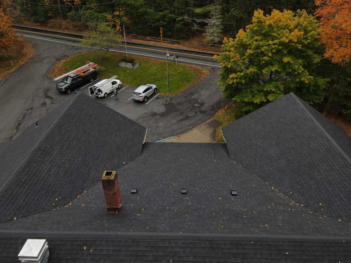 finished roof of building with a parking lot and trees